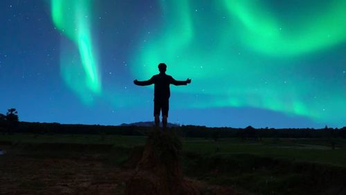 Silhouette man standing on field against sky at night