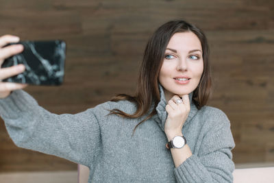 Beautiful young woman taking selfie while sitting in cafe