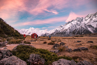 Scenic view of hut on land against snowcapped mountains and sky