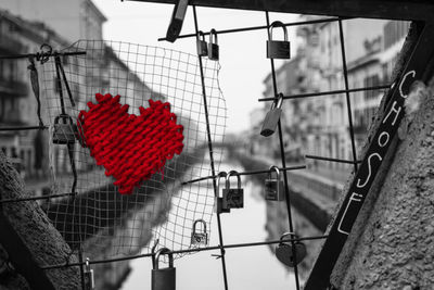 Close-up of heart shape hanging on metal fence