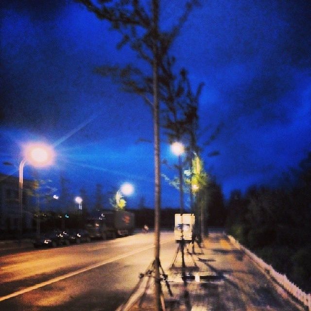 illuminated, night, street light, lighting equipment, transportation, road, the way forward, sky, street, light - natural phenomenon, blue, light trail, electric light, electricity, diminishing perspective, long exposure, motion, tree, light beam, glowing