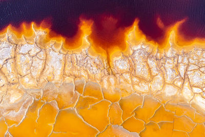 Top view full frame of abstract dried soil textured background with colorful yellow and orange stains creating curved swirls and creative patterns