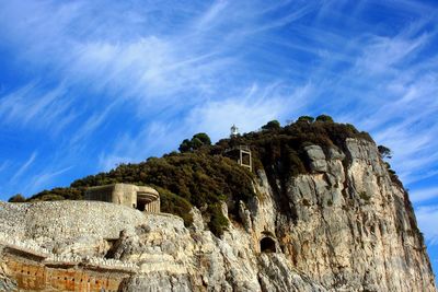 Low angle view of cliff against blue sky