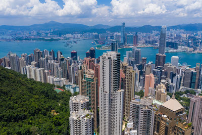 Aerial view of city by sea and buildings against sky