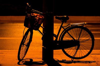 Bicycle parked on street during sunset