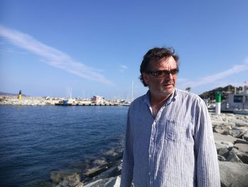 Portrait of man standing by sea against sky