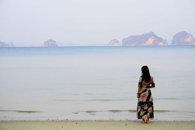 Rear view of woman looking at sea against clear sky