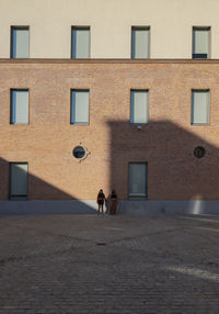 Two young girls with mask standing against brick wall