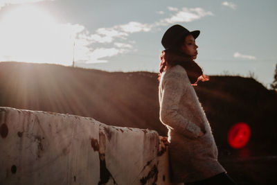 Low angle view of young woman standing against sky