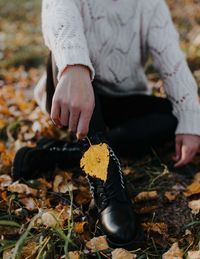 Low section of woman holding dry leaves