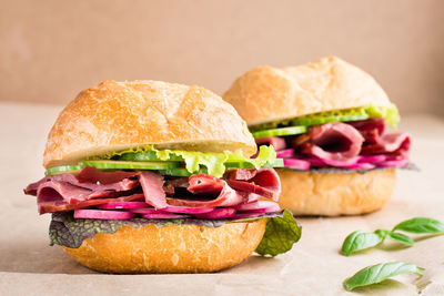 Ready-to-eat hamburger with pastrami, cucumber, radish and herb on craft paper