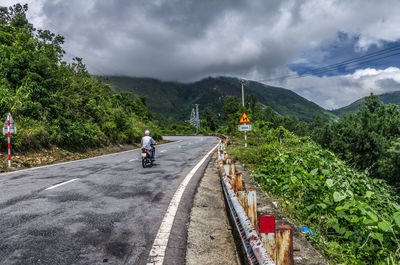 Country road against cloudy sky