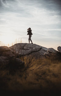 Side view of man standing on rock in the distance