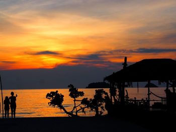 Silhouette woman standing by sea at dusk