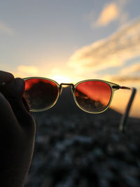 Close-up of sunglasses against sky during sunset