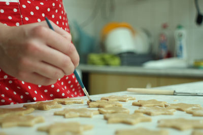 Midsection of woman brushing dough in kitchen