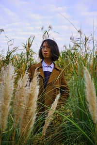 Woman standing amidst plants against sky