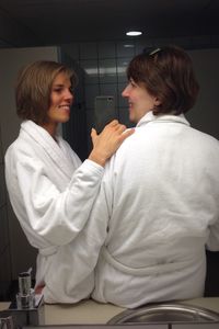 Smiling woman in bathrobes standing against wall