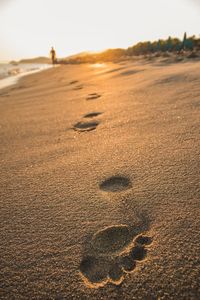 Footprints on sand at beach against sky