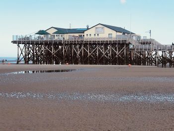 Pier on beach against clear sky