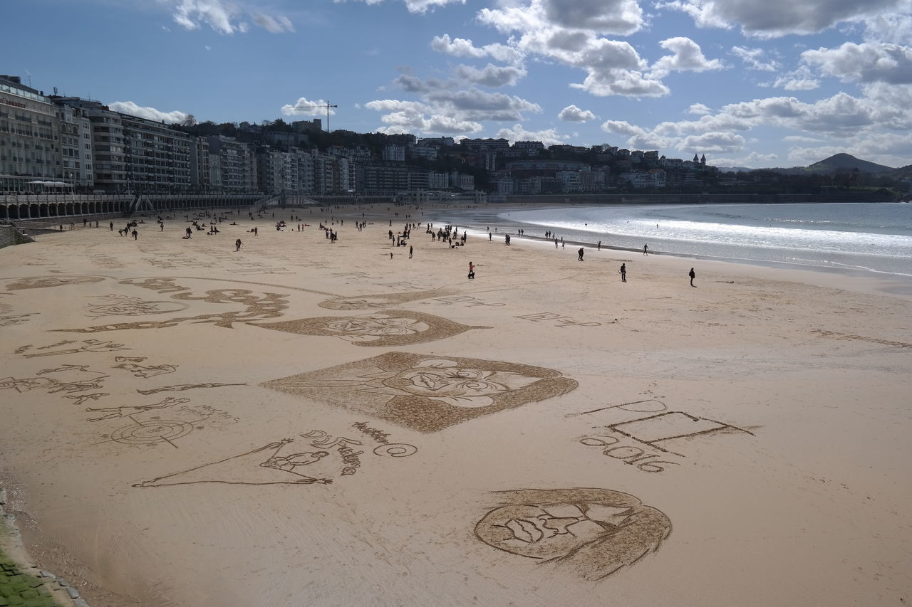 beach, sand, sky, architecture, built structure, building exterior, shore, water, sea, large group of people, cloud - sky, bird, animal themes, incidental people, vacations, tourist, day, city