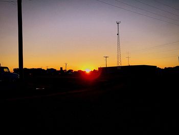 Silhouette electricity pylon against sky during sunset