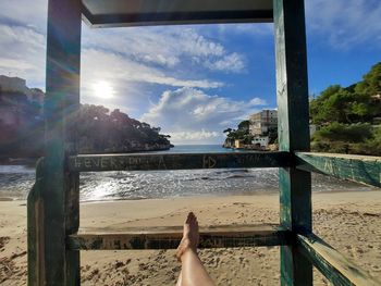 Low section of woman on beach against sky
