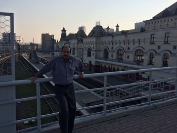 Full length portrait of man standing against railing in city