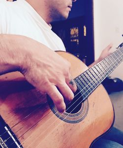 Close-up of man playing guitar at home