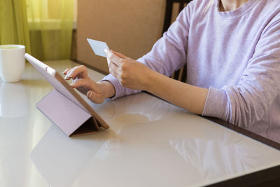 Midsection of man using mobile phone while sitting on table