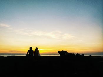 Silhouette people standing on landscape against sky during sunset