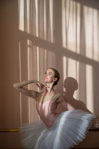 Low angle view of young woman standing against wall