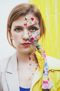 Woman with stickers on face in front of two tone wall