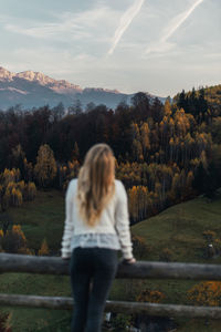 Rear view of woman standing by trees against sky