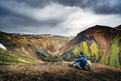 Man sitting on rock against mountains