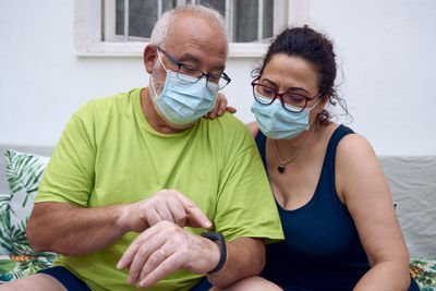 Older couple wearing a surgical masks using a smart watch. concept older people