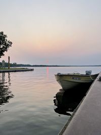 Boat moored in sea against sky during sunset