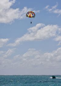 Person paragliding over sea against sky