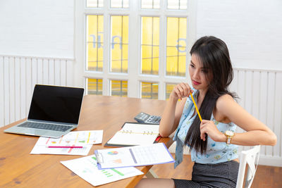 Young woman using phone on table