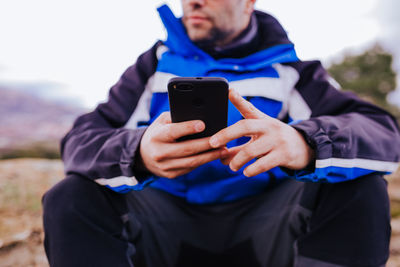 Midsection of man using phone outdoors