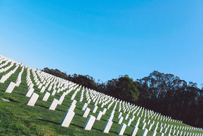 Low angle view of cemetery against clear blue sky