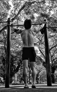 Rear view of shirtless man standing by plants