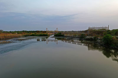 Bridge over river by buildings against sky