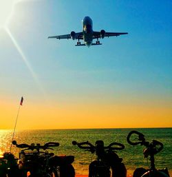 Low angle view of airplane flying over sea against clear sky
