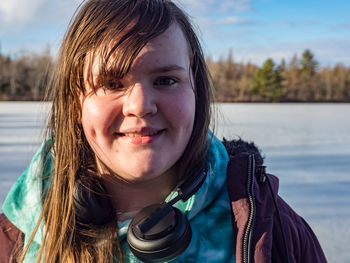 Close-up portrait of smiling girl standing against sky in water