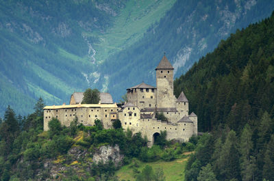 Castle by buildings against mountain