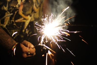 Midsection of man holding lit sparkler