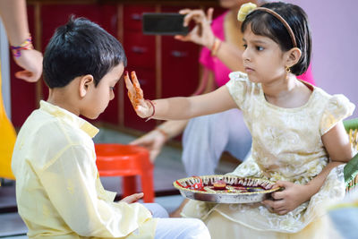 Girl applying tilaka to brother at home