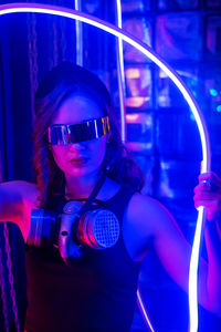 Caucasian woman in sunglasses posing in neon studio