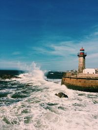Lighthouse by sea against sky